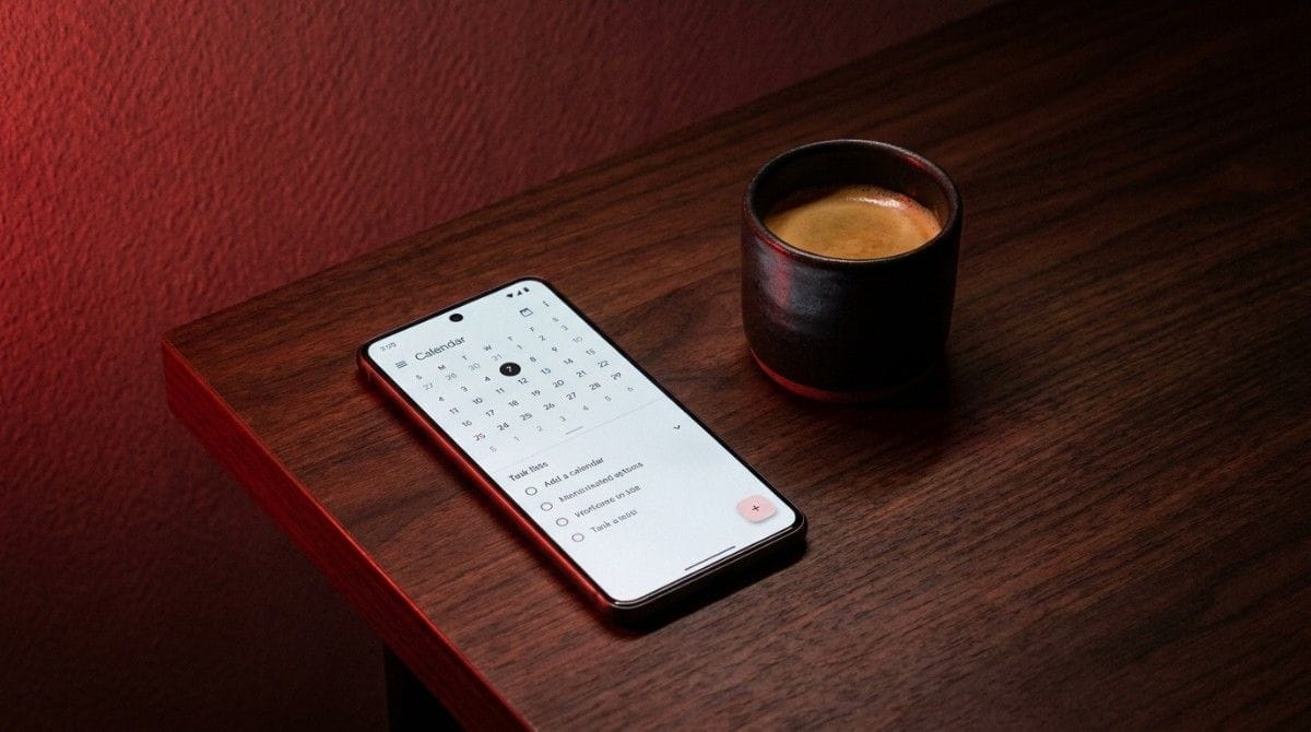 Smartphone displaying a calendar app next to a coffee cup on a wooden table with soft red ambient lighting.
