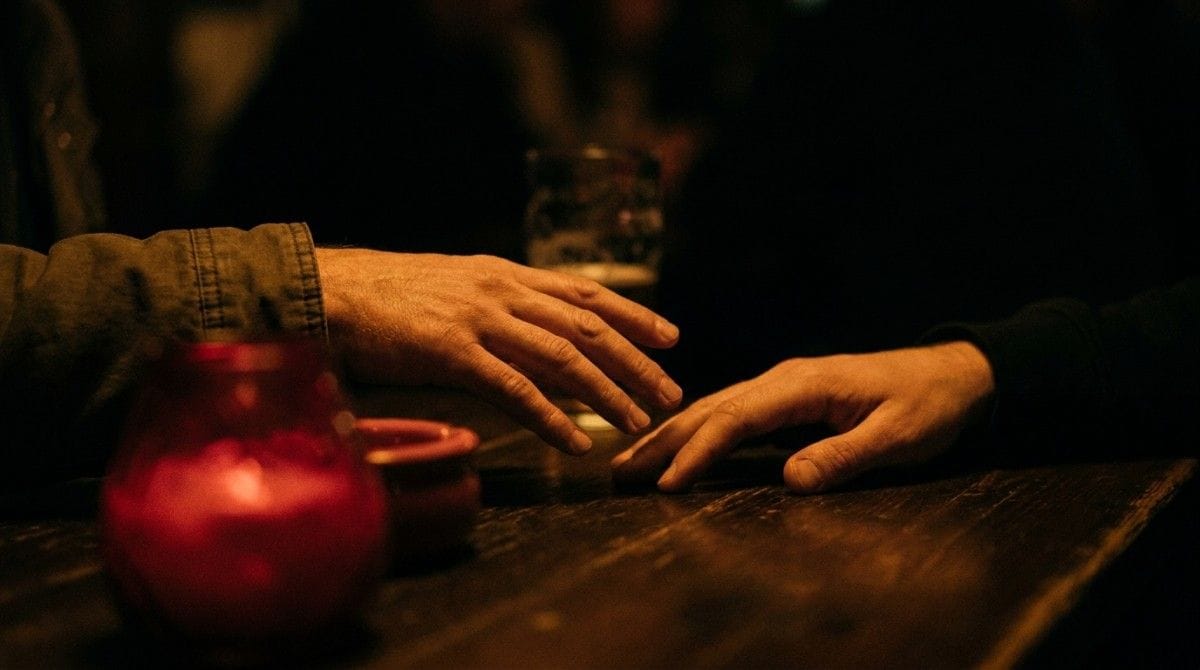 Two hands reach toward each other across a table, symbolizing connection, trust, and emotional support.