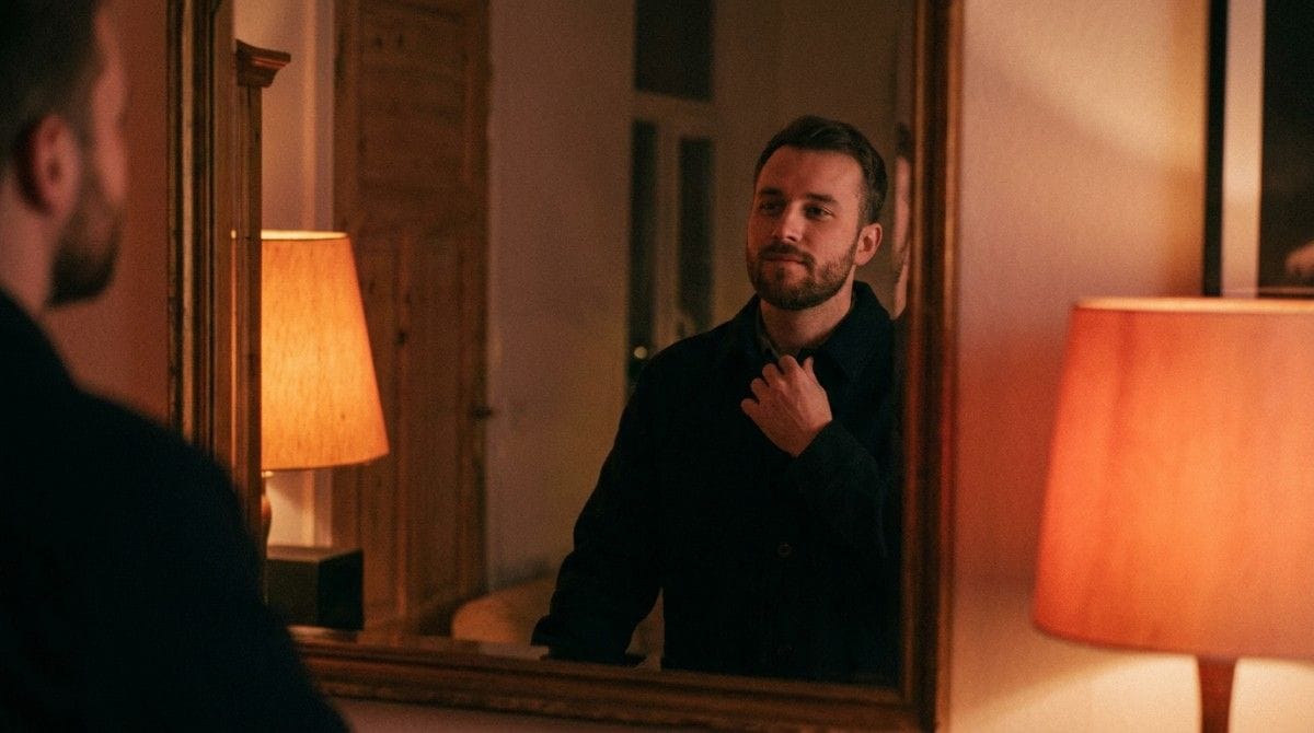 Man adjusting his collar while looking in a mirror before going out in the evening.